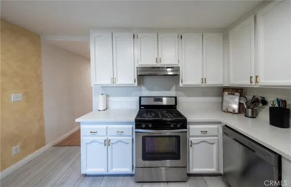 a kitchen with stainless steel appliances granite countertop a stove a white cabinets a sink and dishwasher