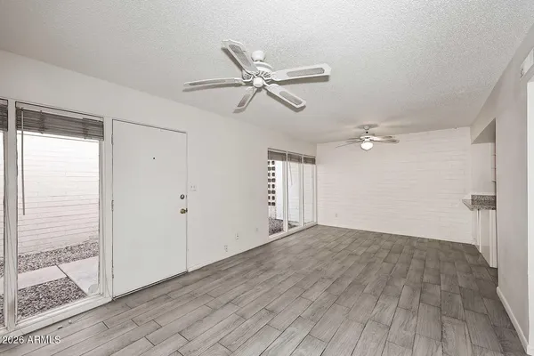 a view of empty room with wooden floor and fan