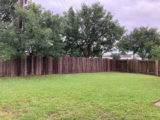 a view of a yard with wooden fence and trees