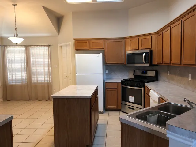 a kitchen with stainless steel appliances granite countertop a stove a sink and a refrigerator