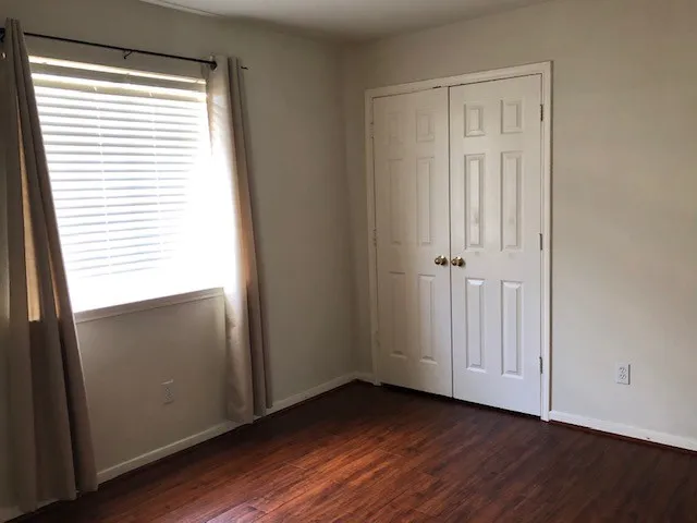 an empty room with wooden floor and window