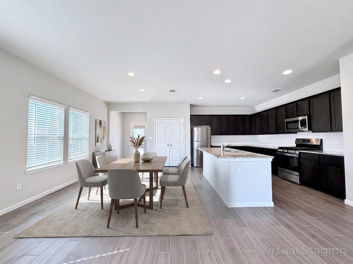 18104 Emu Lane Manor, TX 78653 - Photo 11 of 39 a kitchen with stainless steel appliances granite countertop a stove a sink a microwave refrigerator and a dining table with wooden floor
