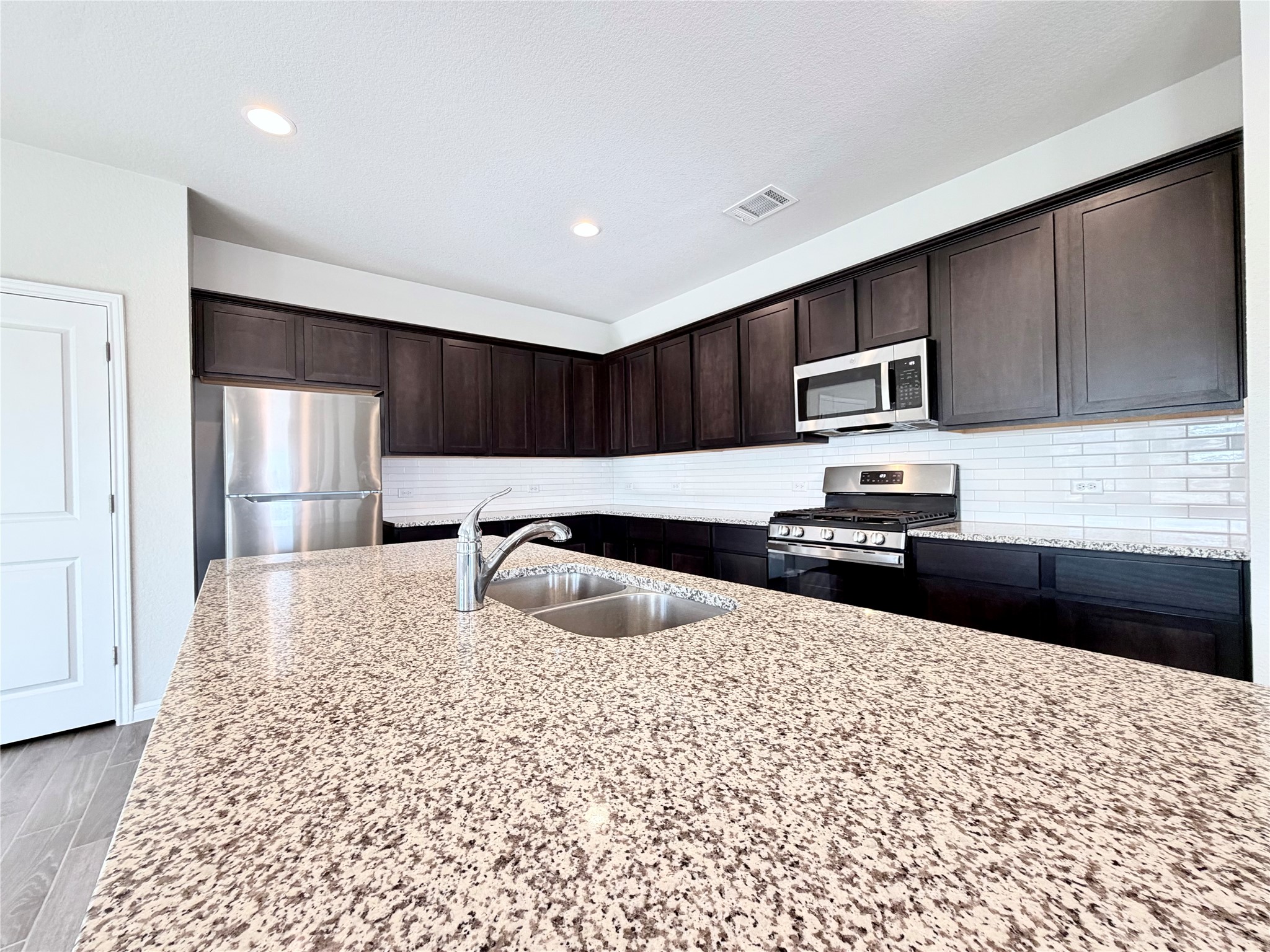 18104 Emu Lane Manor, TX 78653 - Photo 13 of 39 a kitchen with kitchen island granite countertop a sink stove and refrigerator