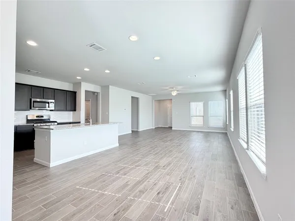 a view of kitchen with kitchen island wooden floors and stainless steel appliances