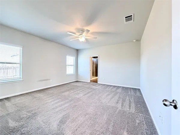 an empty room with windows and fan