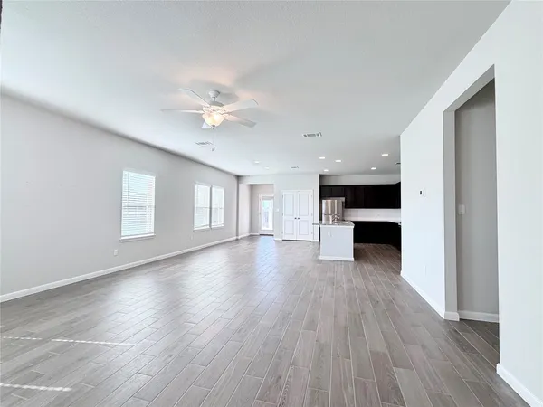 a view of an empty room with a kitchen and wooden floor