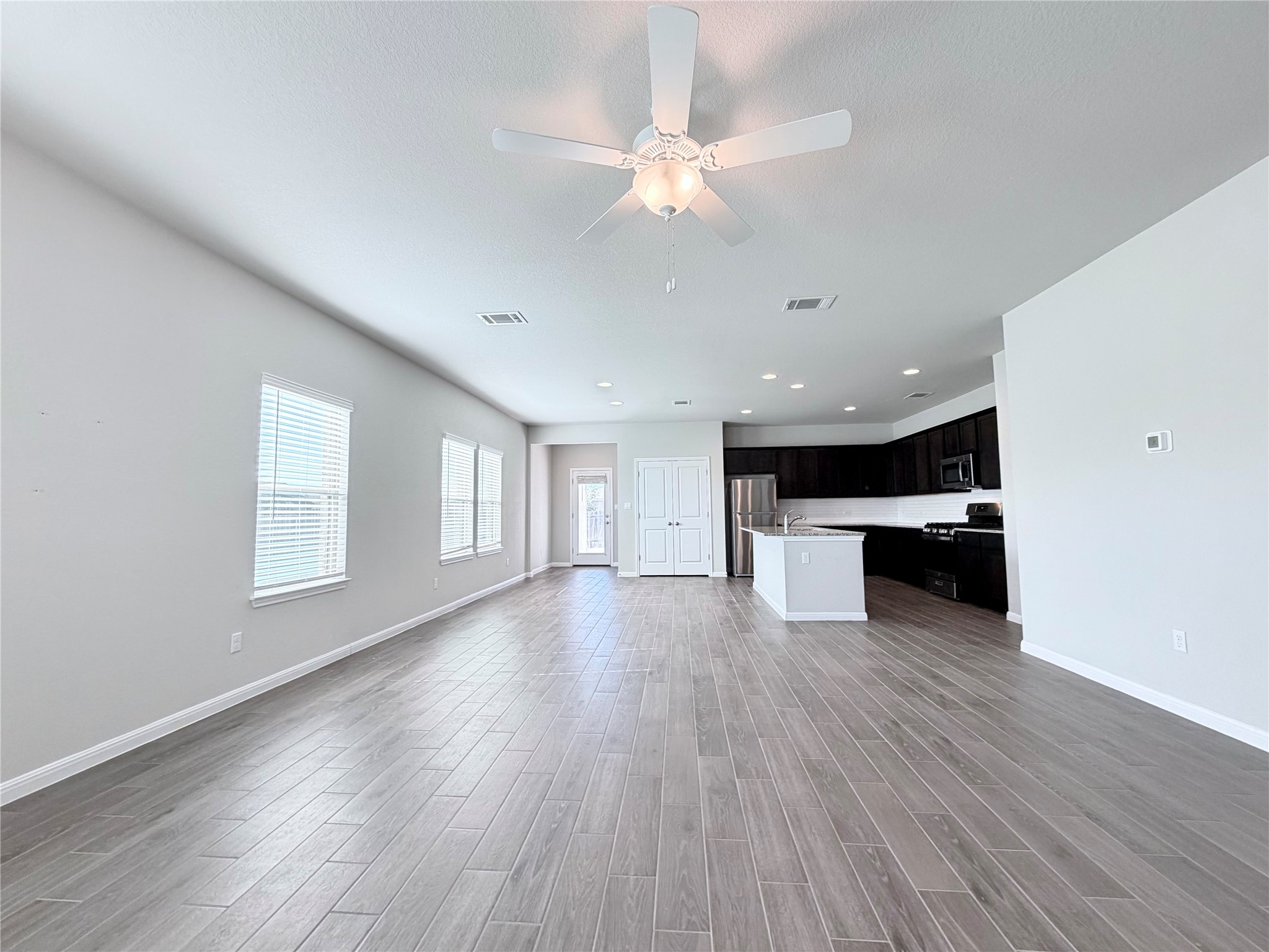 18104 Emu Lane Manor, TX 78653 - Photo 6 of 39 a view of an empty room with wooden floor and a kitchen