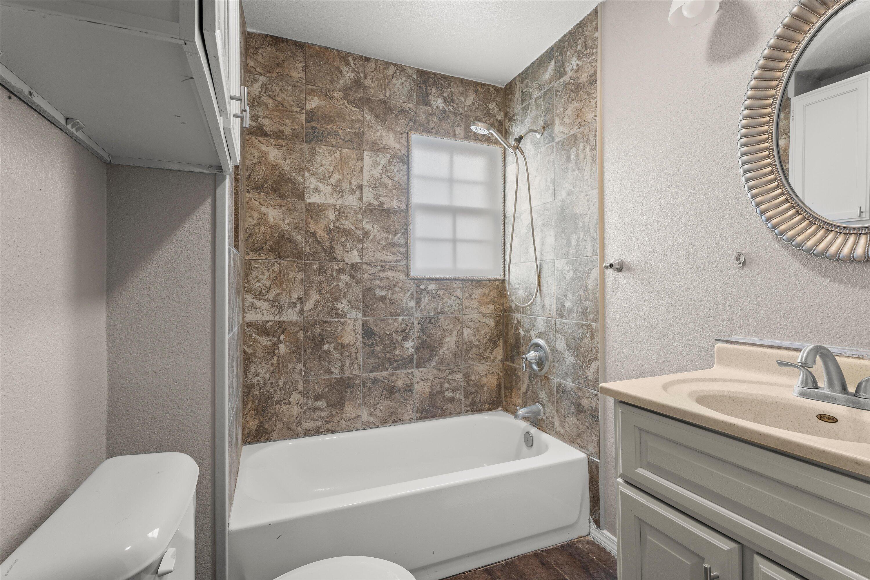 204 Ave L Levelland, TX 79336 - Photo 18 of 27 a bathroom with a bathtub a sink a toilet and a mirror