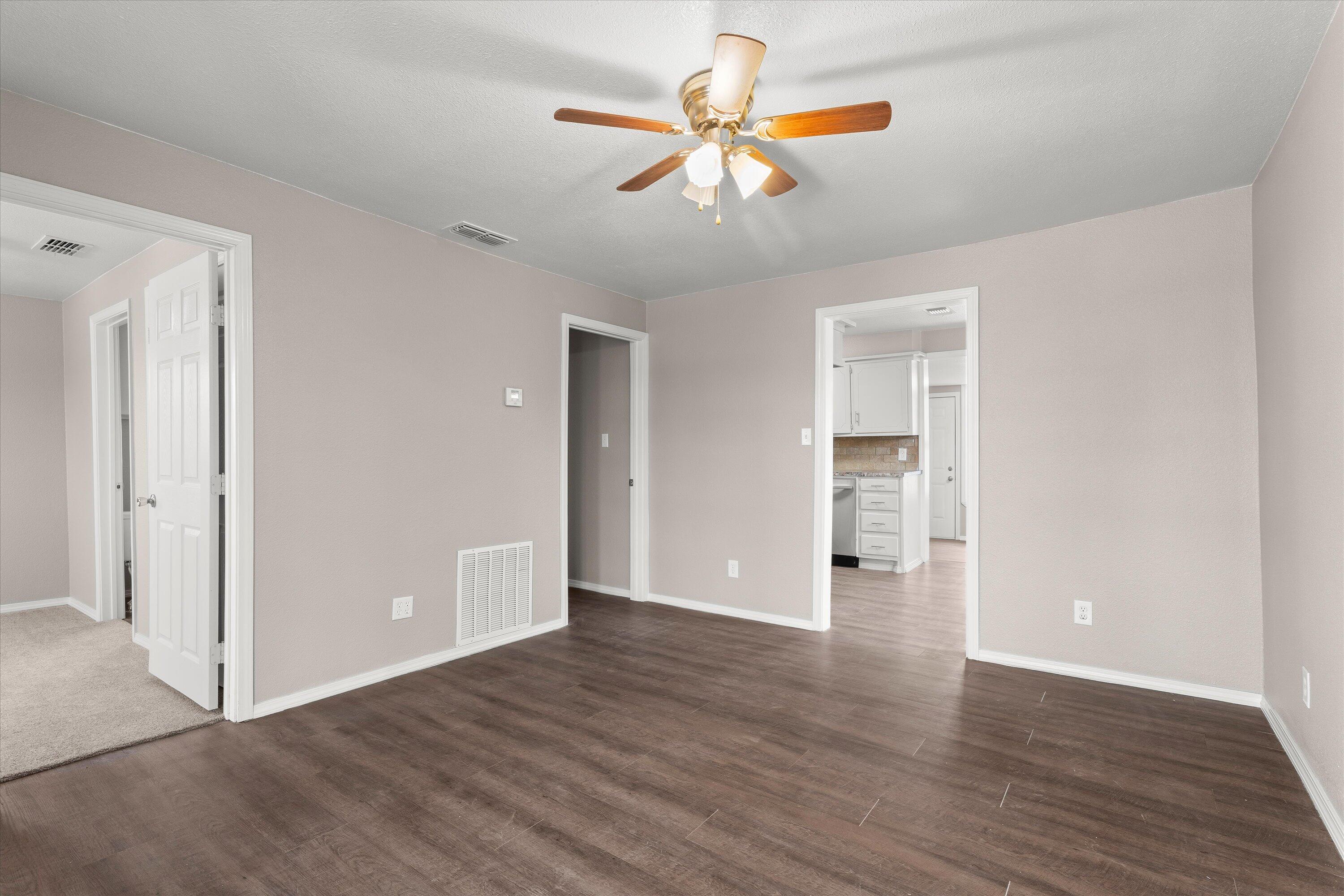 204 Ave L Levelland, TX 79336 - Photo 4 of 27 an empty room with wooden floor chandelier fan and windows