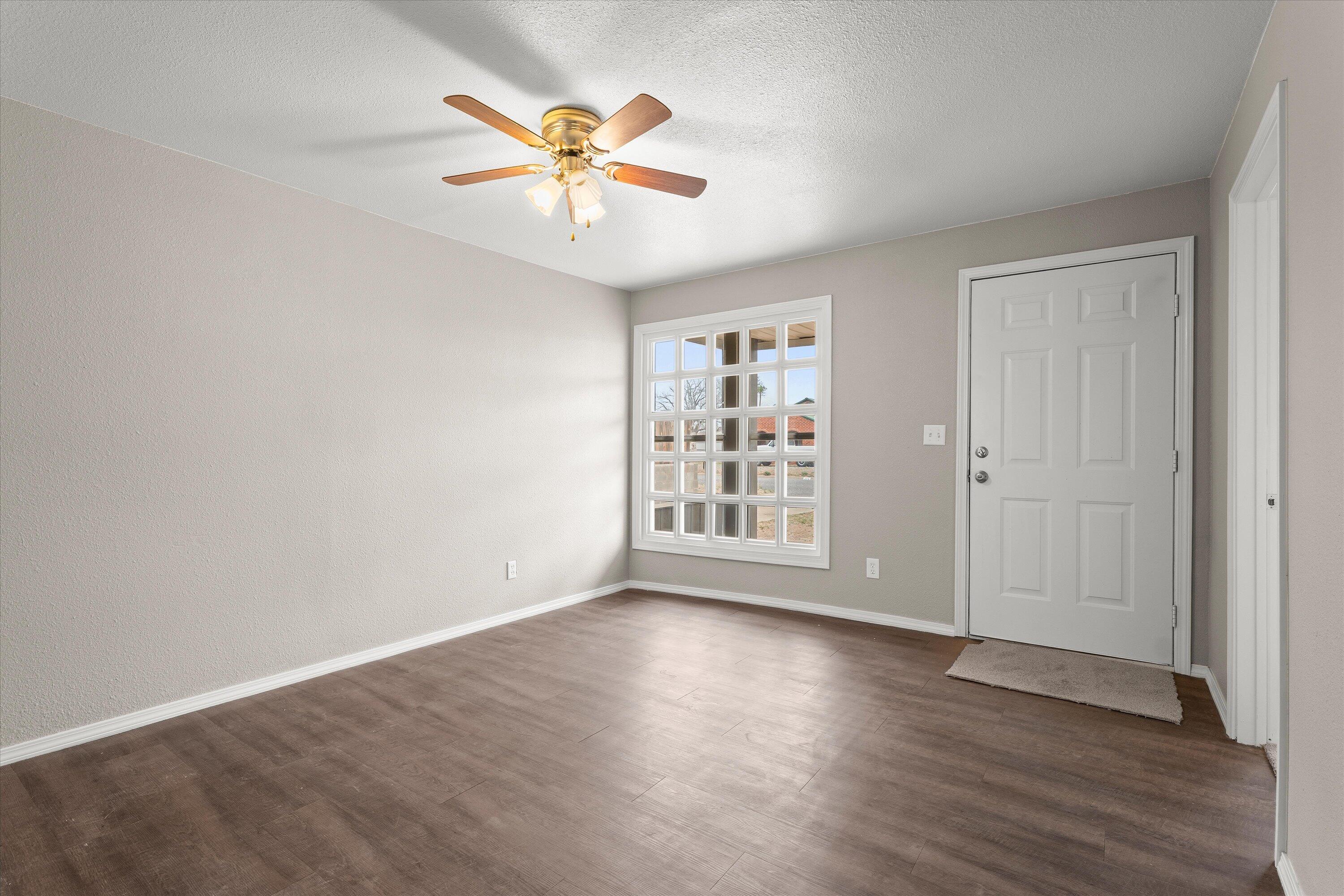 204 Ave L Levelland, TX 79336 - Photo 6 of 27 an empty room with wooden floor chandelier fan and windows