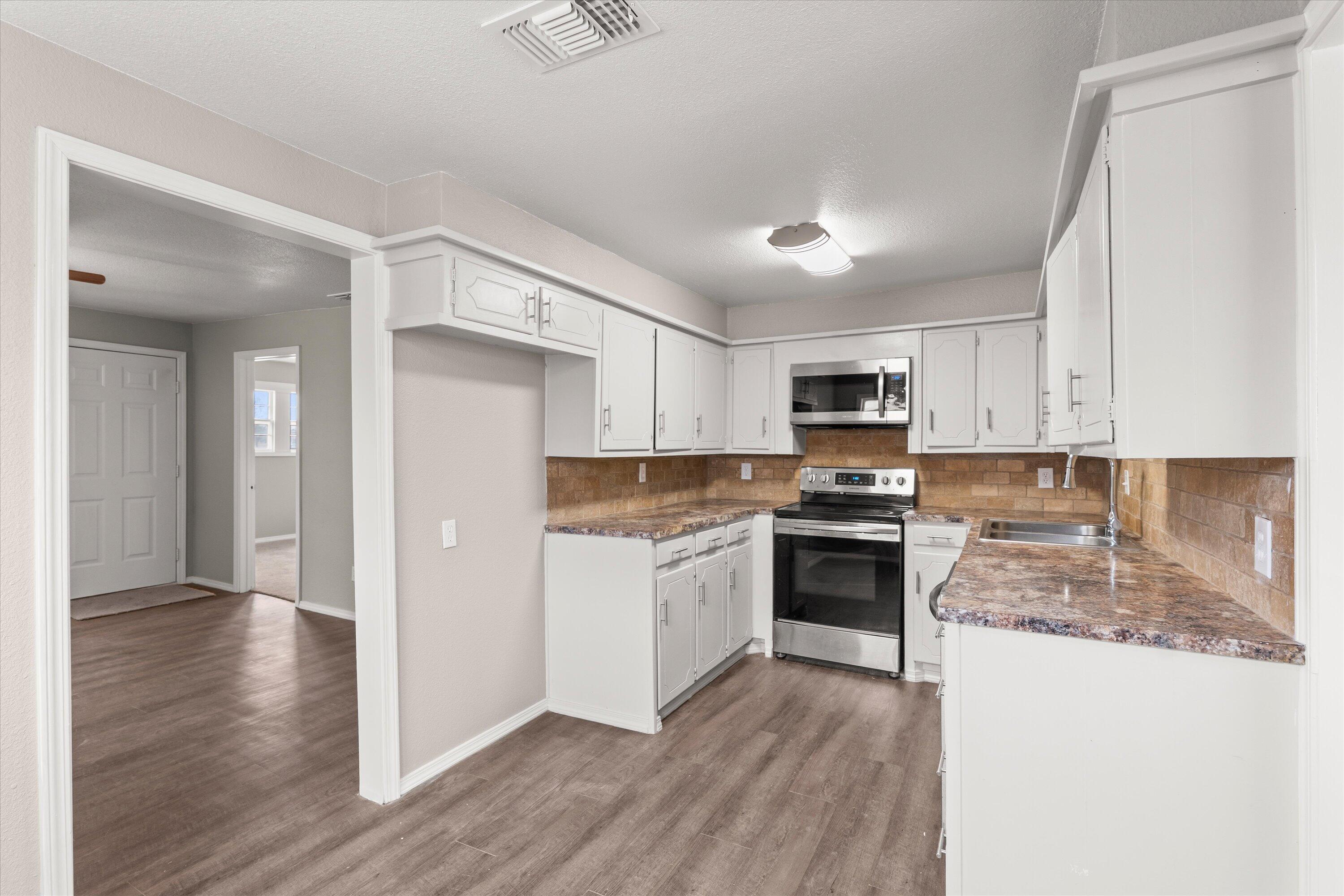 204 Ave L Levelland, TX 79336 - Photo 7 of 27 a kitchen with a refrigerator stove top oven and sink