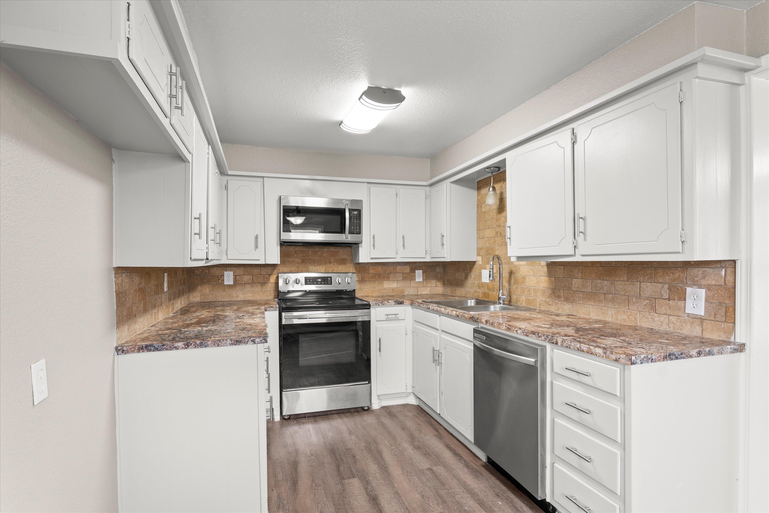 204 Ave L Levelland, TX 79336 - Photo 8 of 27 a kitchen with granite countertop white cabinets and white appliances
