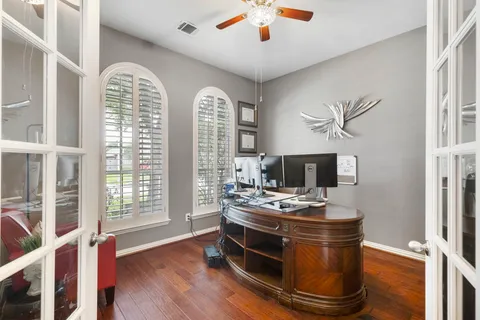 a room with chandelier fan and wooden floor