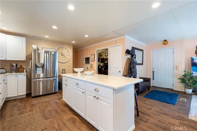 a large kitchen with kitchen island a refrigerator a stove a sink dishwasher a oven with a dining table and chairs with wooden floor