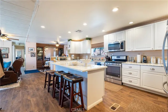 a kitchen with stainless steel appliances kitchen island granite countertop a table chairs sink and cabinets