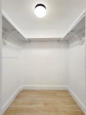 an empty room with wooden floor and ceiling fan
