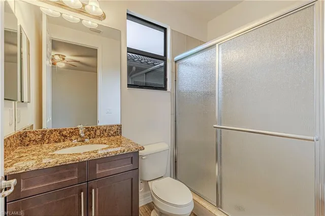 a bathroom with a granite countertop sink a toilet a mirror and shower