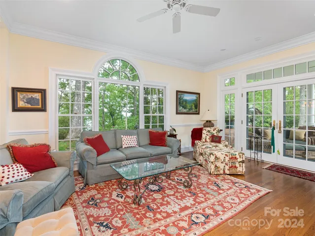 a living room with furniture large windows and wooden floor