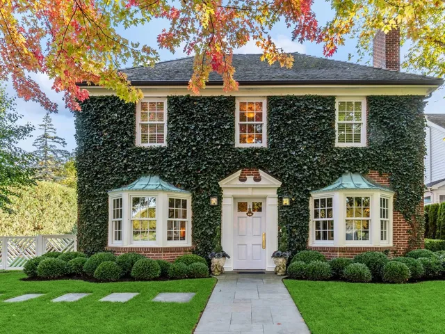 a front view of a house with a yard and trees