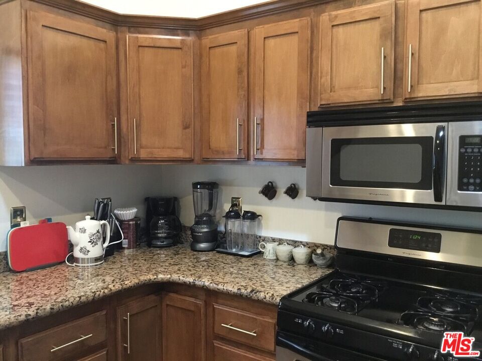 Undisclosed Address Desert Hot Springs, CA 92240 - Photo 27 of 44 a kitchen with granite countertop stainless steel appliances a stove microwave and cabinets