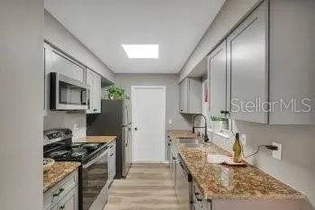 a kitchen with granite countertop stainless steel appliances stove microwave and sink