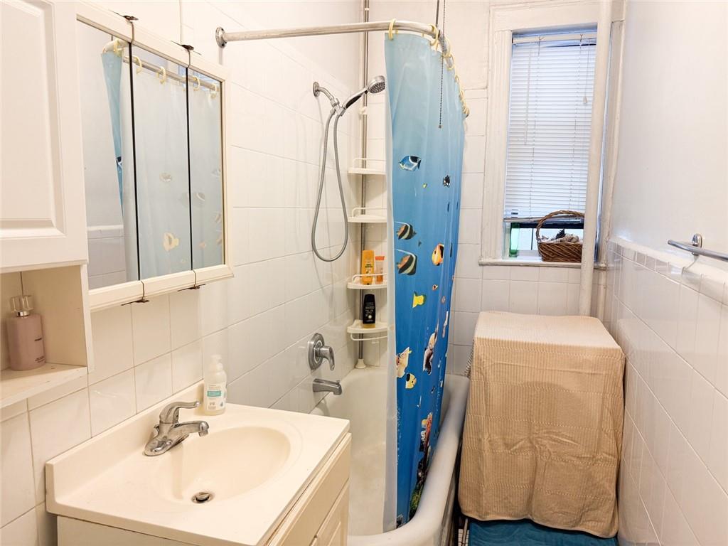 3039 Ocean Parkway, Unit B6 Brooklyn, NY 11235 - Photo 9 of 12 a bathroom with a sink a mirror a bathtub and shower