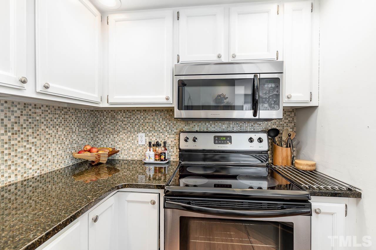 1400 Barton Pl Drive Raleigh, NC 27608 - Photo 10 of 25 a kitchen with granite countertop a stove top oven microwave and cabinets