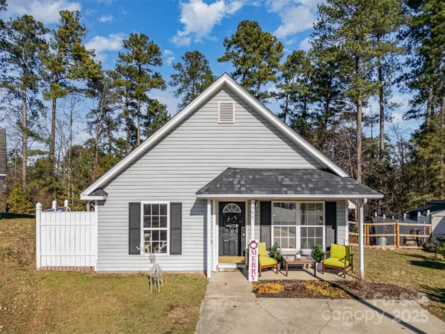 a view of a house with backyard outdoor seating and covered with trees
