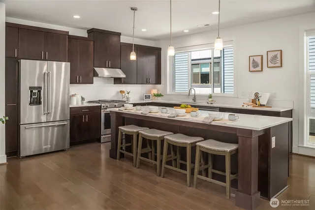 a kitchen with stainless steel appliances granite countertop a table chairs stove microwave and refrigerator