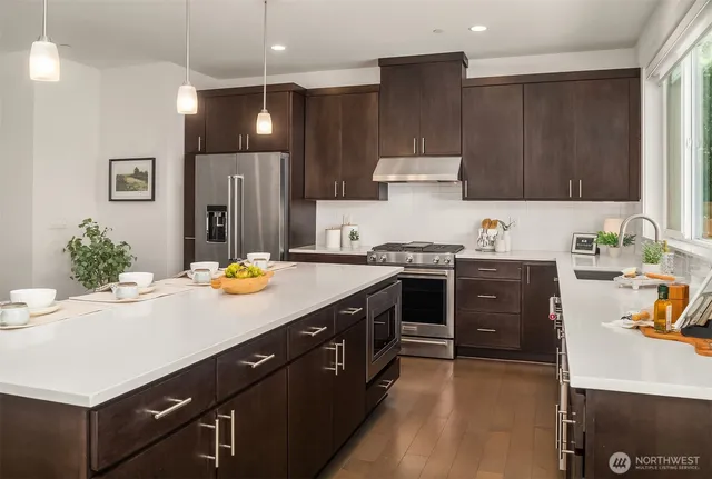 a kitchen with kitchen island granite countertop a sink a stove and refrigerator