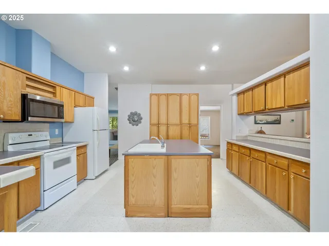 a kitchen with stainless steel appliances granite countertop a stove top oven a sink dishwasher and a refrigerator with wooden floor