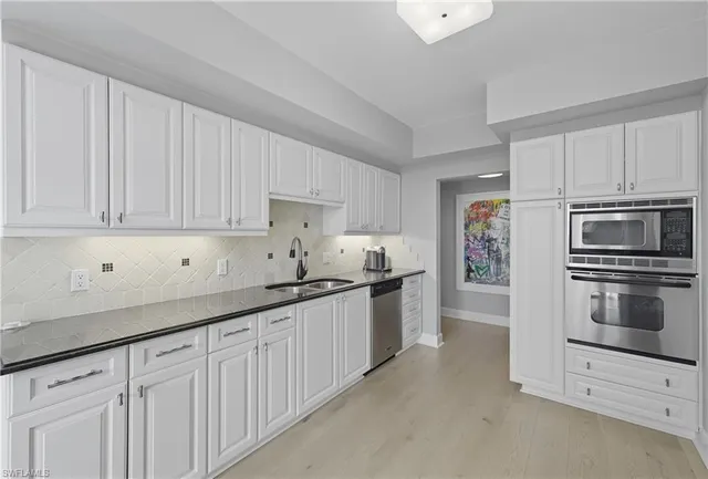 a kitchen with granite countertop white cabinets and stainless steel appliances