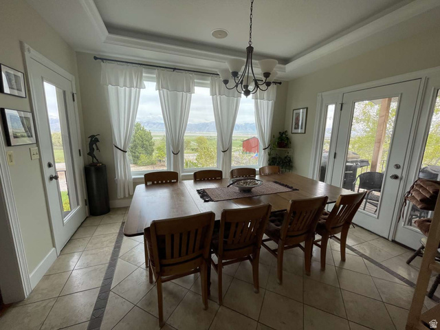 7030 West 2100 North Mendon, UT 84325 - Photo 24 of 67 Dining area featuring a tray ceiling with a chandelier, tile flooring with a decorative inlay, and multiple French doors