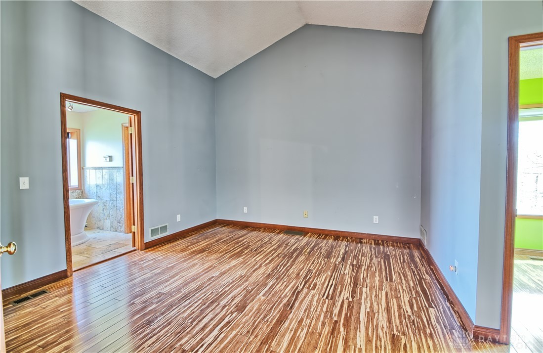 8711 Nicole Lane Springboro, OH 45066 - Photo 35 of 87 This primary bedroom features high vaulted ceilings and rich hardwood flooring, offering a peaceful retreat.