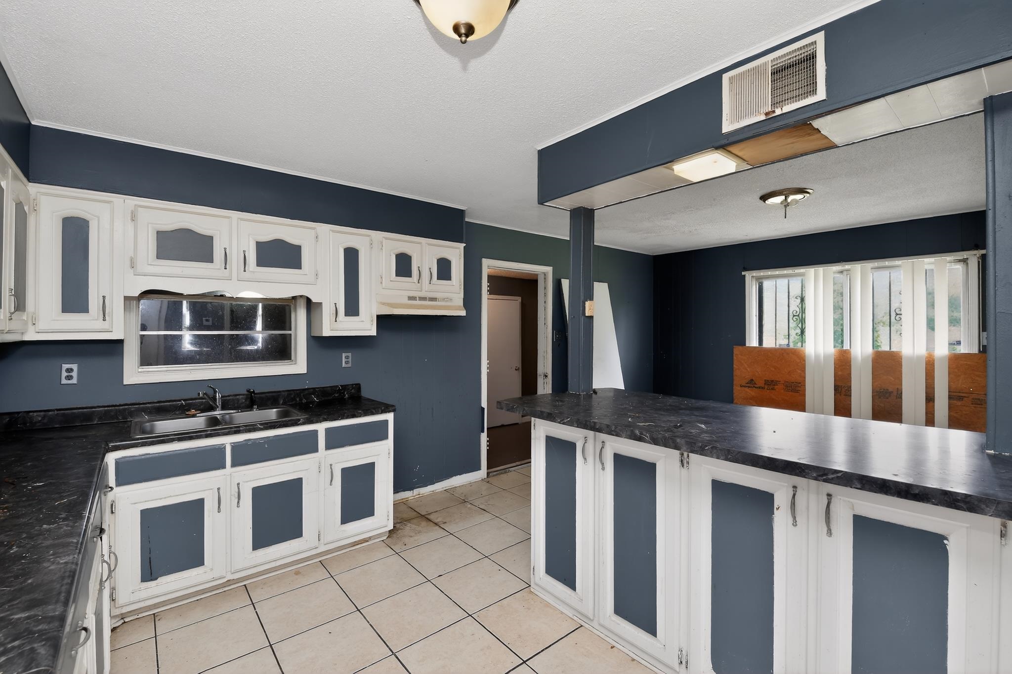 645 Parkrose Road Memphis, TN 38109 - Photo 11 of 32 Kitchen featuring white cabinetry with dark panel inserts, dark countertops, and a double basin sink under a window
