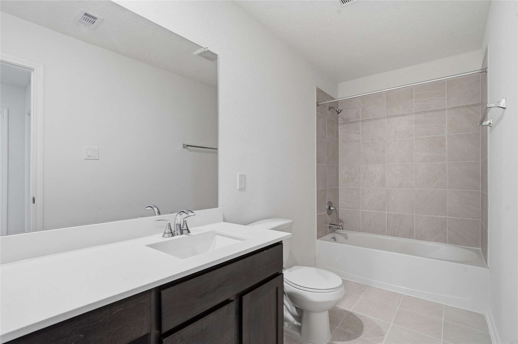 2503 Spruce Hl Road Beasley, TX 77417 - Photo 23 of 31 The secondary bathroom offers tile flooring, a bath/shower combination with a stylish tile surround, rich stained wood cabinetry with added knee space and elegant light countertops, a mirror, and sleek fixtures with modern finishes.