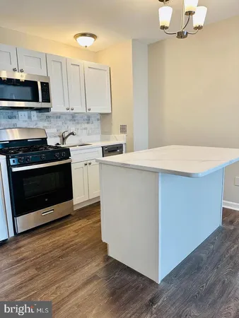 a kitchen with stainless steel appliances a stove a microwave and white cabinets