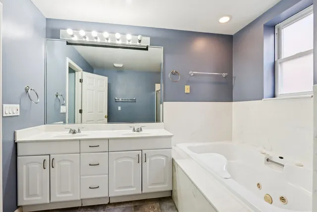 a bathroom with a tub a sink and mirror