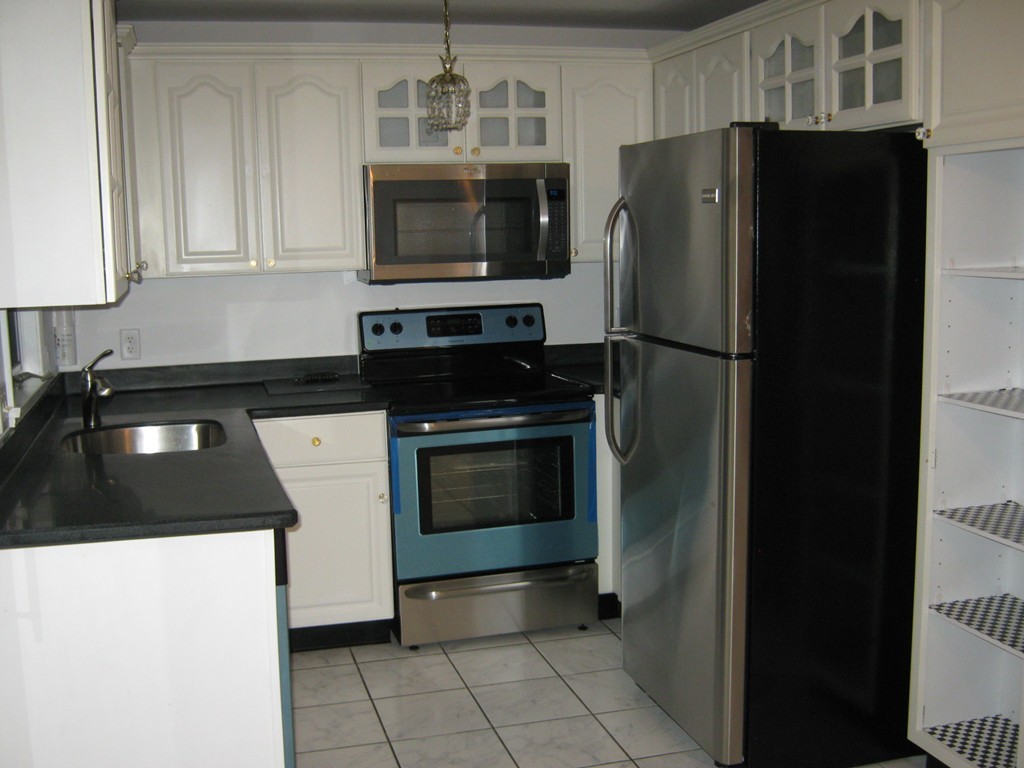 a kitchen with granite countertop a refrigerator and a stove top oven
