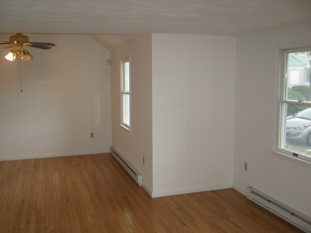 65 Victoria Heights Road, Unit 65 Boston, MA 02136 - Photo 3 of 16 an empty room with wooden floor and windows