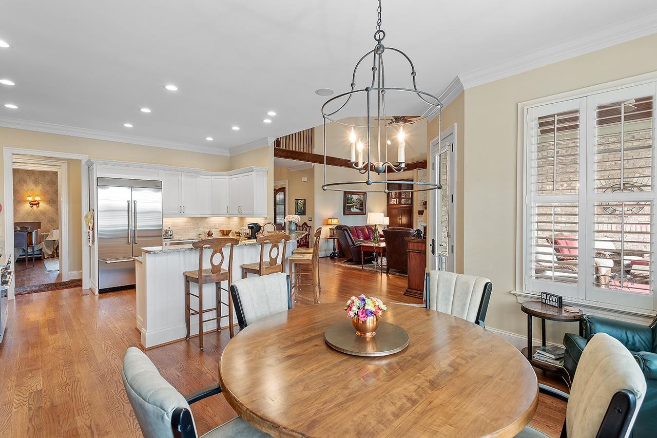 1116 Hunting Ridge Road Raleigh, NC 27615 - Photo 32 of 91 a dining room with wooden floor a chandelier a glass table and chairs