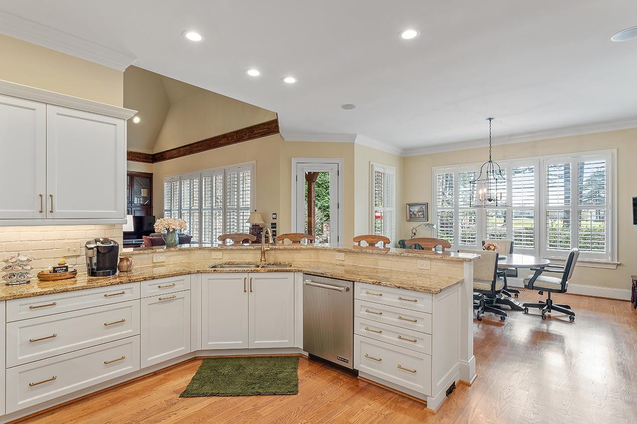 1116 Hunting Ridge Road Raleigh, NC 27615 - Photo 37 of 91 a kitchen with a stove a sink and white cabinets with wooden floor