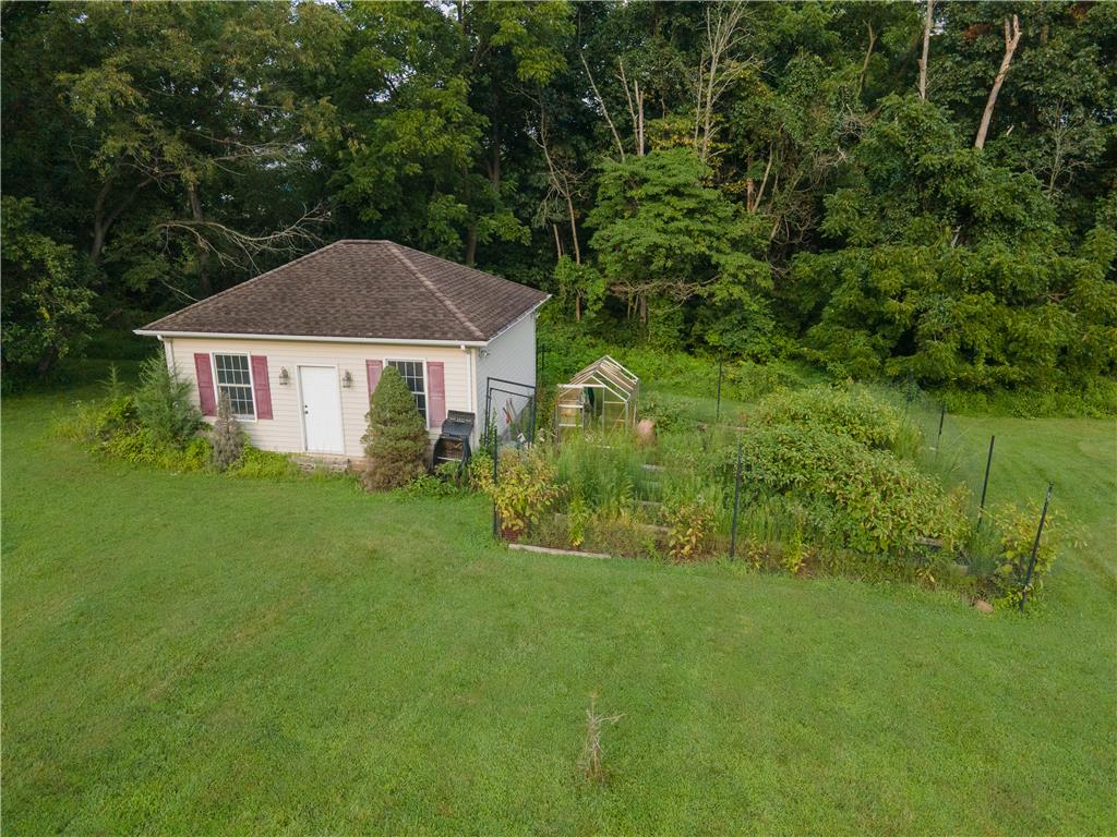 2202 High Meadow Road Coopersburg, PA 18036 - Photo 39 of 41 An detached outbuilding stands alongside a garden area bordered by mature trees.