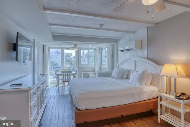 a bedroom with a bed a lamp and a large window with wooden floor