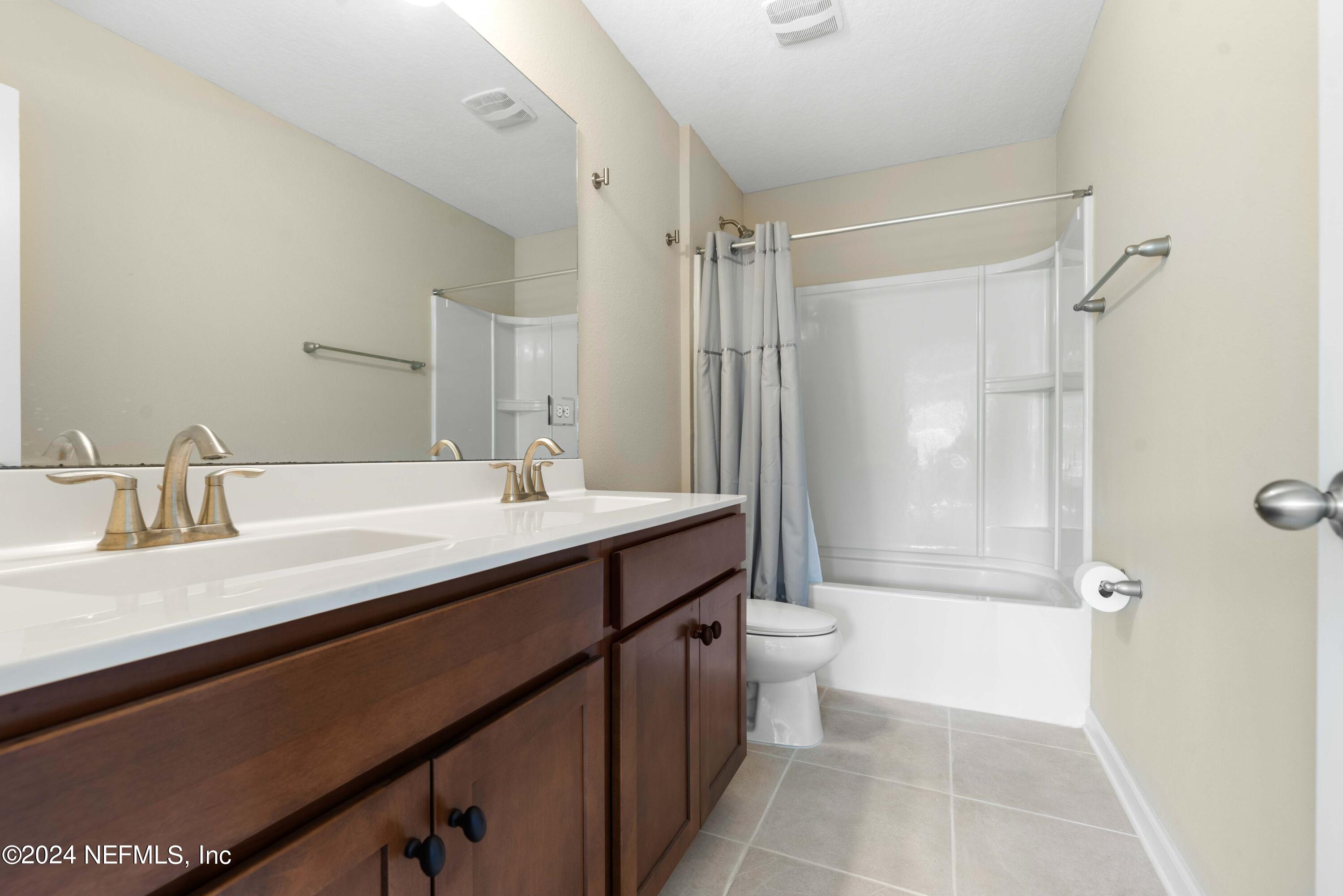 245 Floco Avenue Yulee, FL 32097 - Photo 21 of 38 a bathroom with a double vanity sink toilet mirror and shower