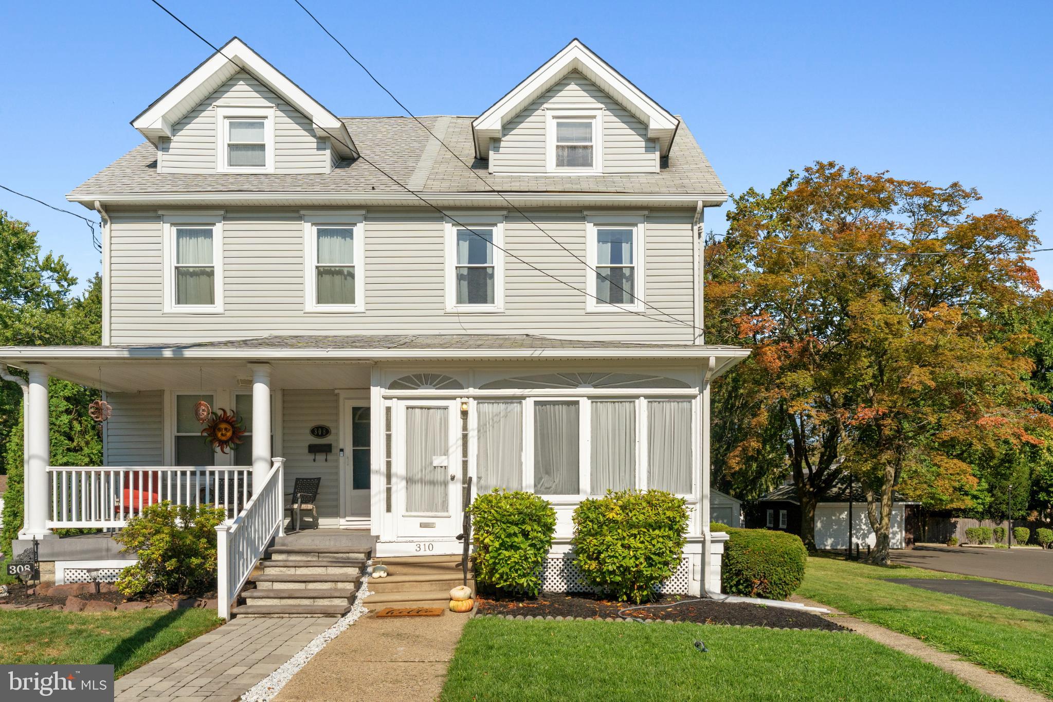 a view of a brick house with large windows and a yard with plants and large trees