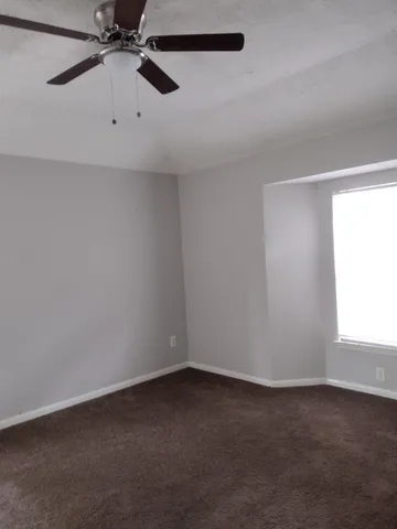 an empty room with a window and a ceiling fan
