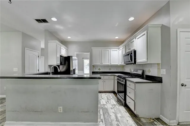 a kitchen with stainless steel appliances white cabinets and a stove top oven