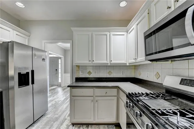 a view of a kitchen with stainless steel appliances granite countertop a stove and cabinets