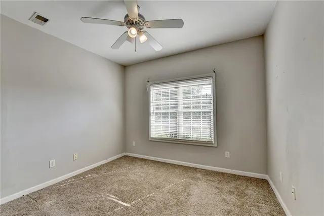 a view of an empty room with window and chandelier fan